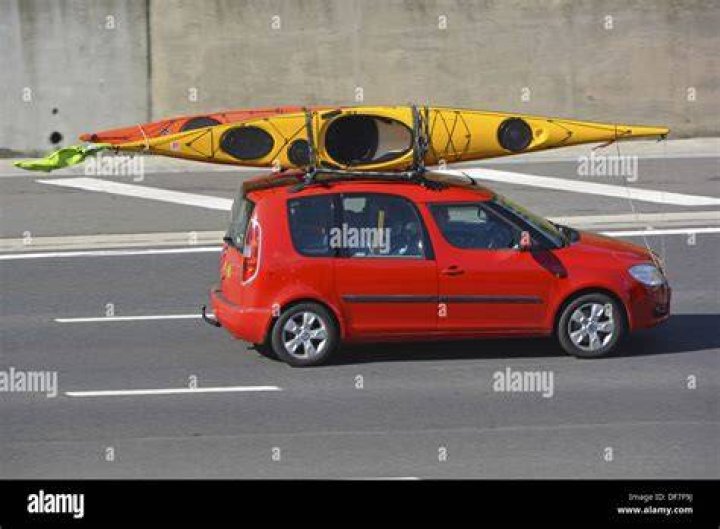 A Car with Kayak Loaded on Top enters through Tall Garage Doors
