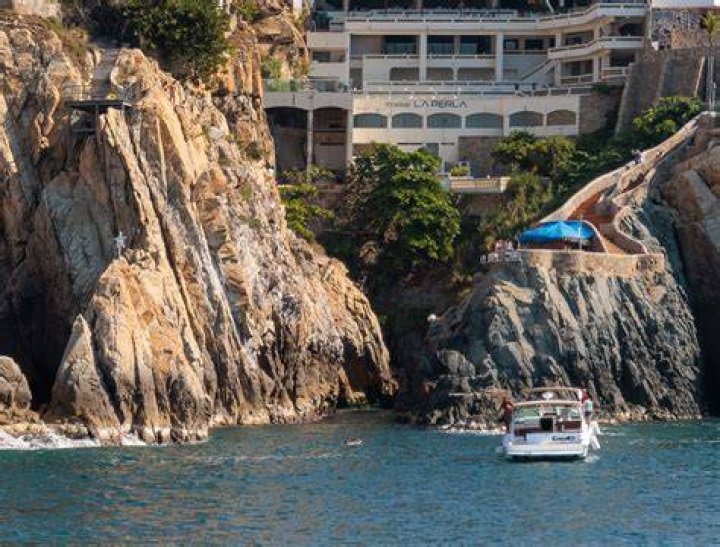 A cliff diver in Acapulco, Mexico walks past a shrine set up near the ledge where daredevils plunge into the Pacific