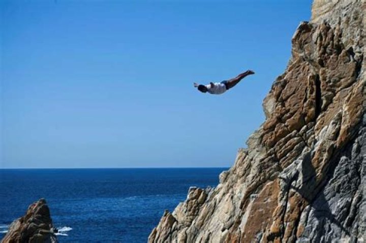 A cliff diver leaps from the rocks above Acapulco after the Mexican resort allowed resumption of the activity in the aftermath of deadly Hurricane Otis, but tourists are only slowly returning to the region