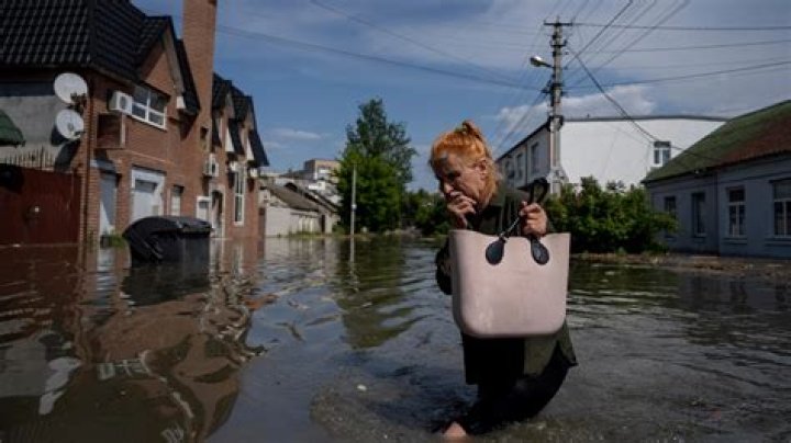 A local resident makes her way through a flooded road after the walls of the Kakhovka dam collapsed in Kherson, Ukraine. Photo / AP