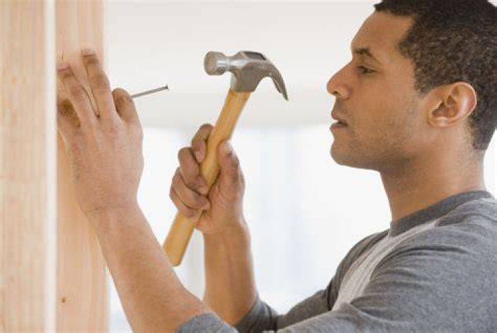 a person hammering a nail on shingles