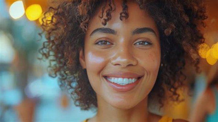 A smiling person uses a laptop in an autumn garden