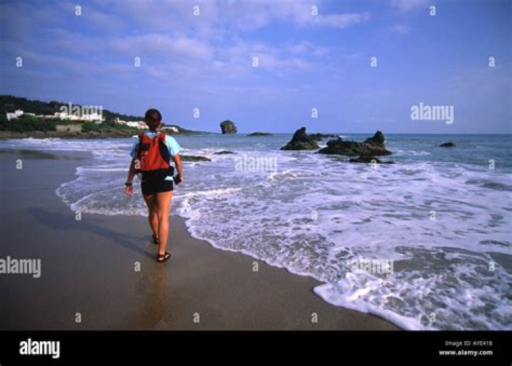 A tourist walks along the shore as forensic workers surround the body of a murdered man at Hornos beach. Photo / Getty