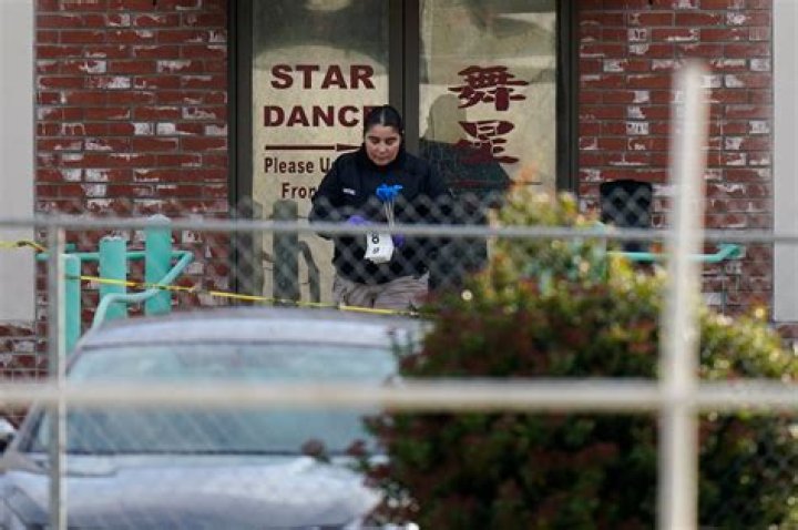 An investigator carries markers outside Star Dance Studio in Monterey Park where a mass shooting took place setting off a manhunt for the suspect. Photo / AP