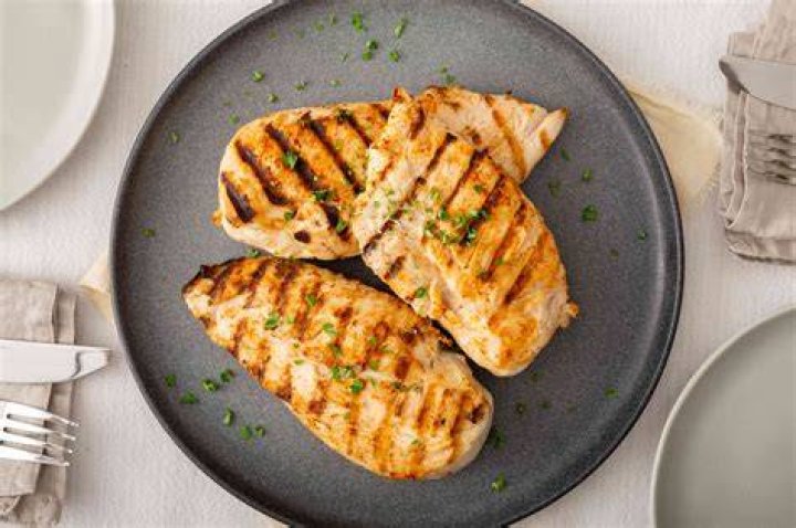grilled chicken breast in different variations with cherry tomatoes, green french beans, garlic, herbs, cut lemon on a teflon pan