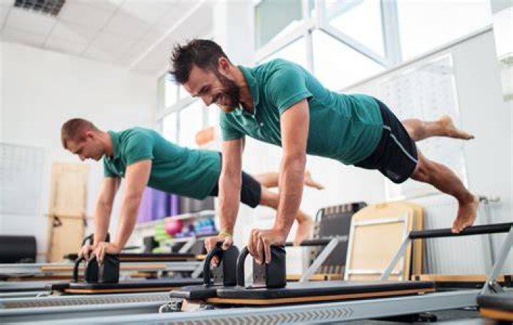 Group of men doing Pilates exercises on bosu balls.