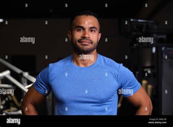 hispanic strong man in gym picking up weights hispanic strong man in gym picking up weights