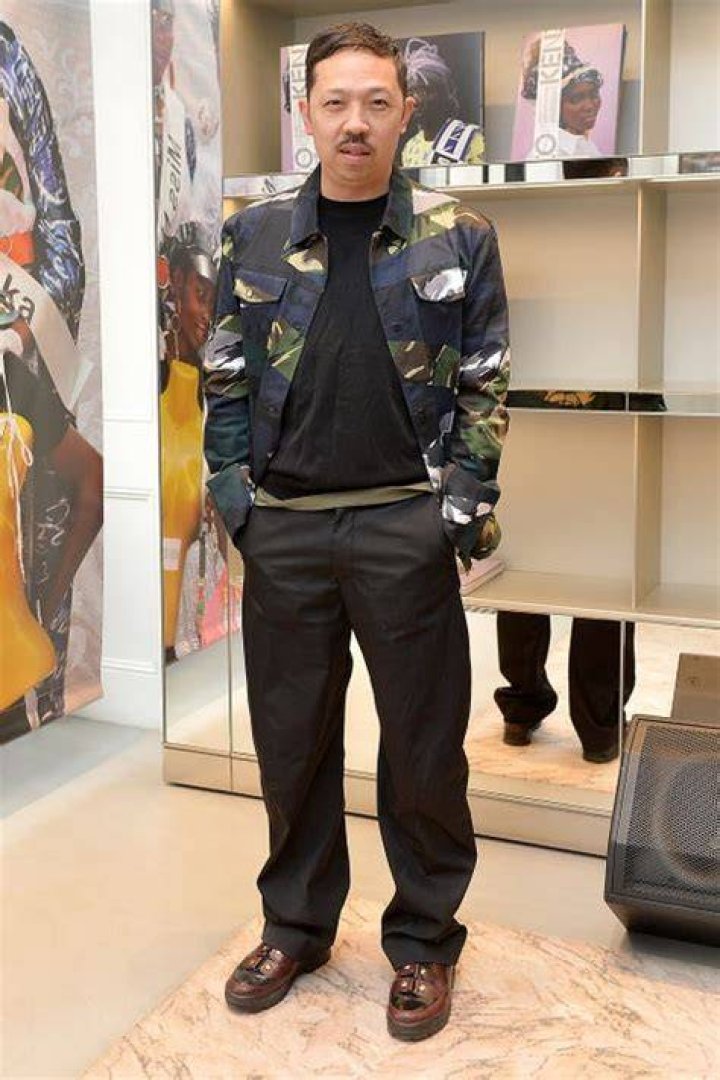 humberto leon wears a camo jacket, a black tee over an olive tee, black pants, and oxblood shoes