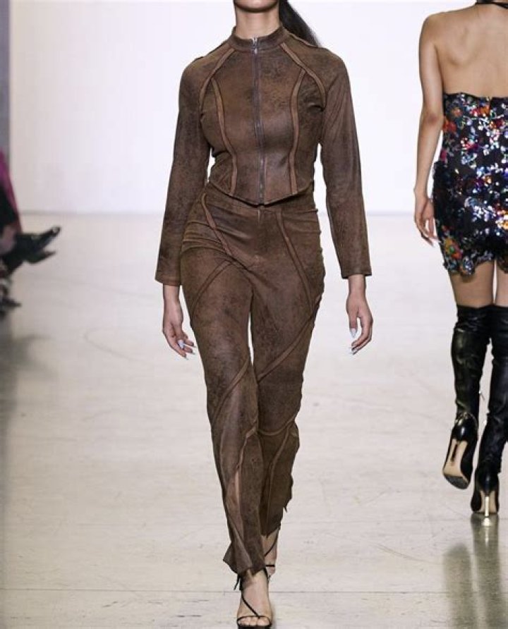 kim shui in brown leather pants, a beige tube top, and a diamond necklace