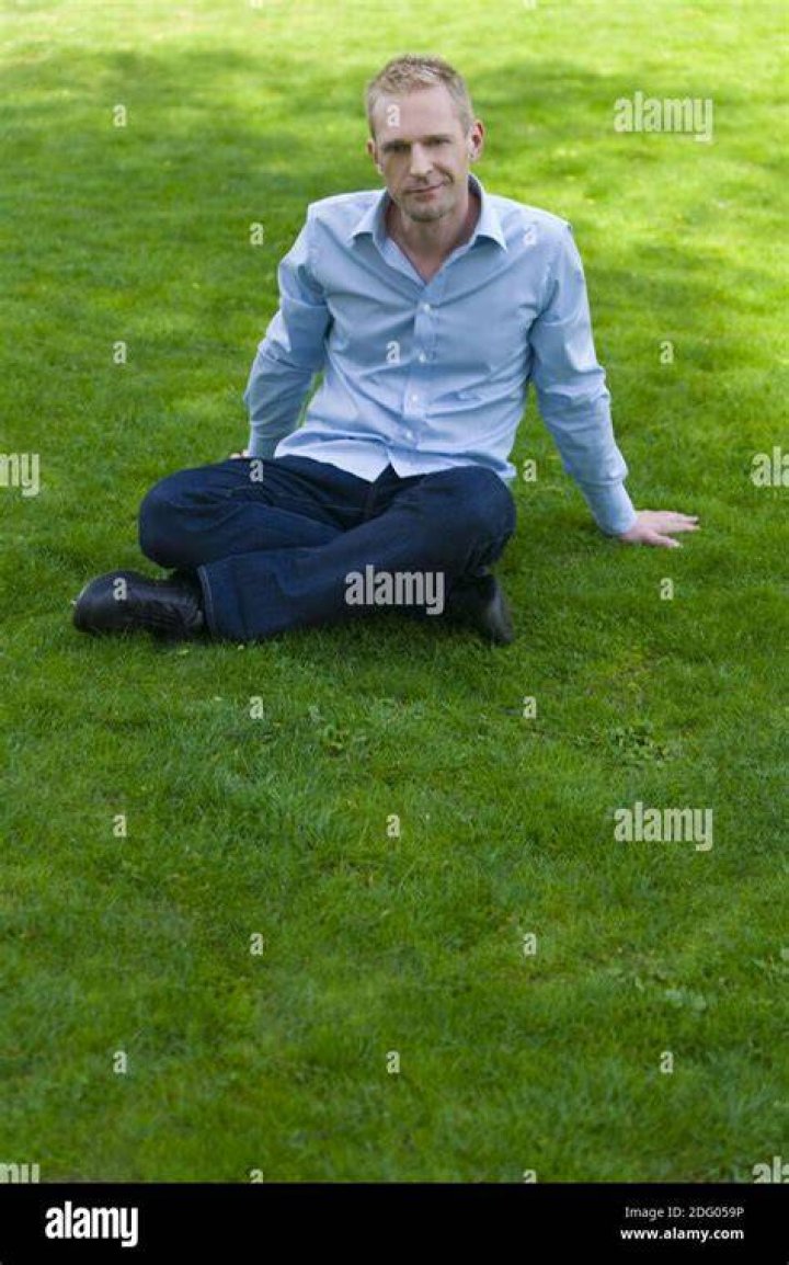 man sitting on a meadow eating mixed salad, partial view