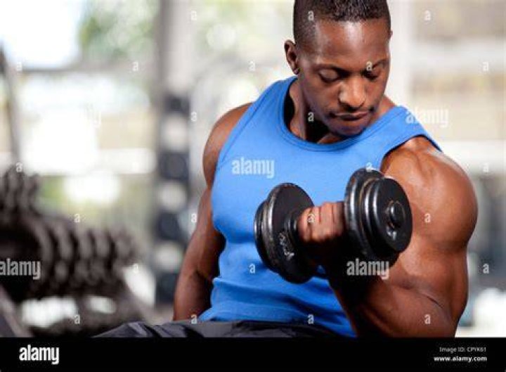 muscular young man lifting weights outside barbell curl