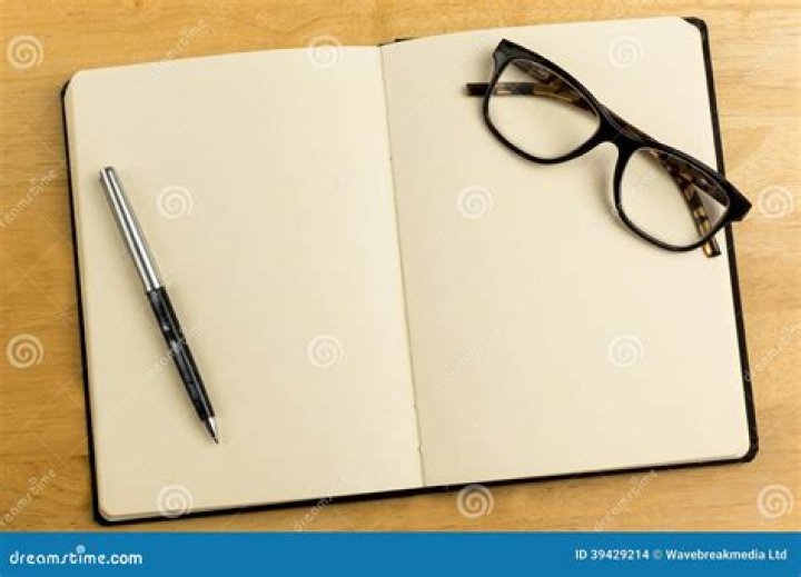 open notebook with glasses on top and laptop behind