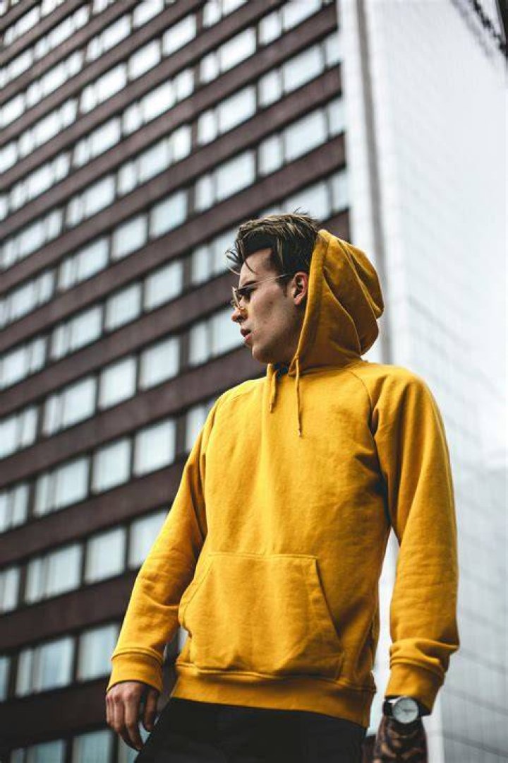person in a yellow hoodie and sunglasses hiking with a backpack