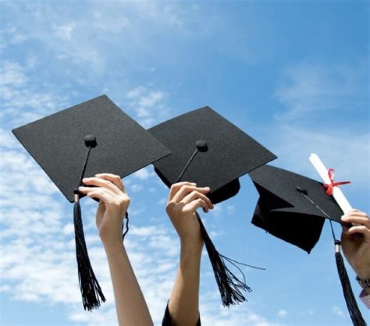 person wearing college cap and gown blows confetti