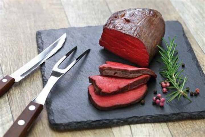 Raw steak meat from deer on the bridlic chopping board with ingredients as a sea salt, pepper , rosemarine, oil and hunting hat as a decoration. raw steak meat from deer on the bridlic chopping board with ingredients as a sea salt, pepper , rosemarine, oil and hunting hat as a decoration