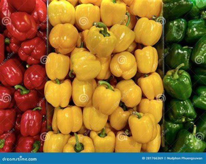 red, yellow and green bell peppers are seen stacked side by side in a farmers market display