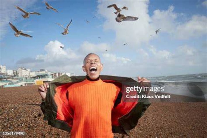 senior man screaming while birds flying at beach on sunny day