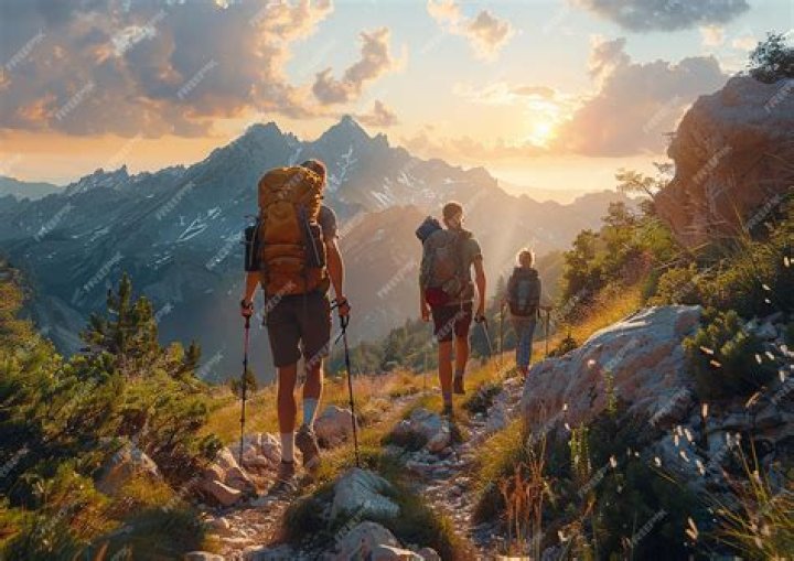 three people hiking in mountain landscape with water in the background
