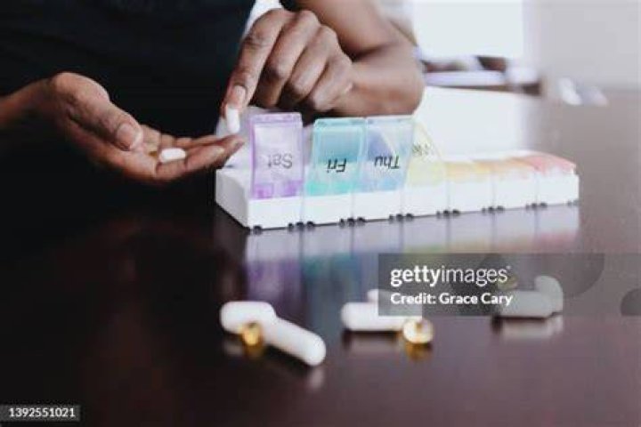 woman organizes her daily dose of pillssupplements with multicolored pill container