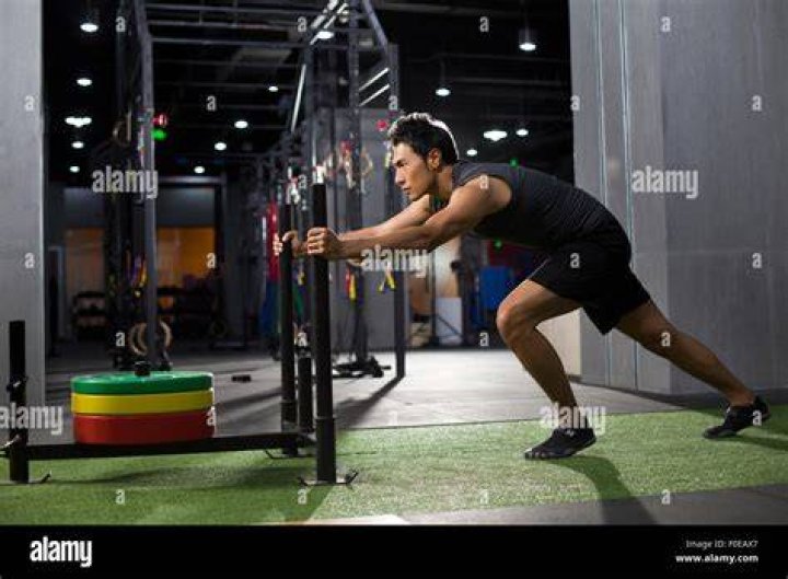young man pushing weight sled at gym